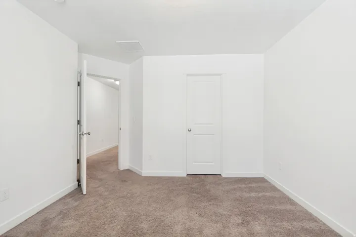 Carpeted room with white walls, a white two-panel interior door, and white trim