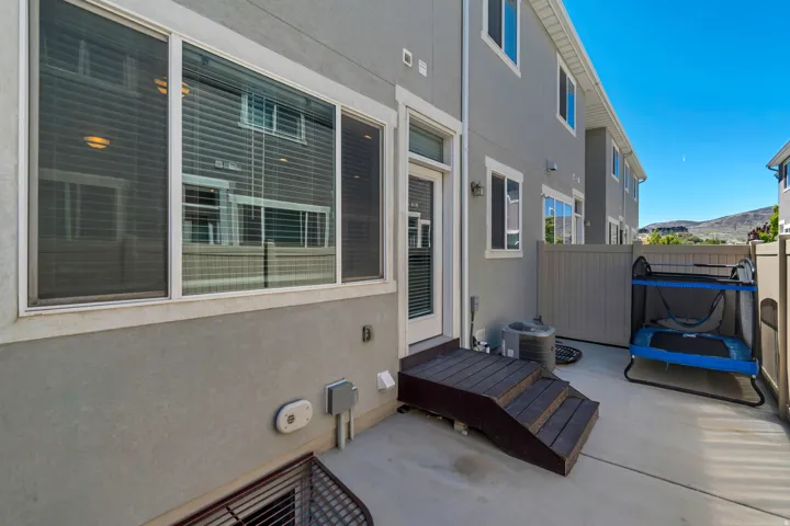 Rear patio with concrete surface, privacy fencing, and wood-finish steps