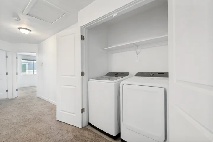 Dedicated laundry closet featuring a white shelf for storage and included white appliances