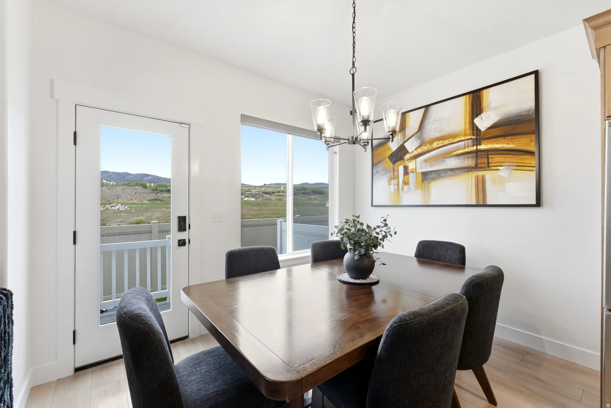 Dining area featuring wood-finish flooring, a contemporary chandelier, and a framed abstract art piece