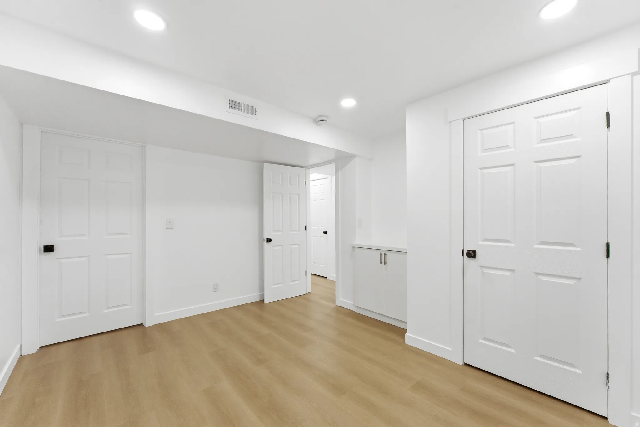 Light wood-finish flooring complemented by white trim and doors