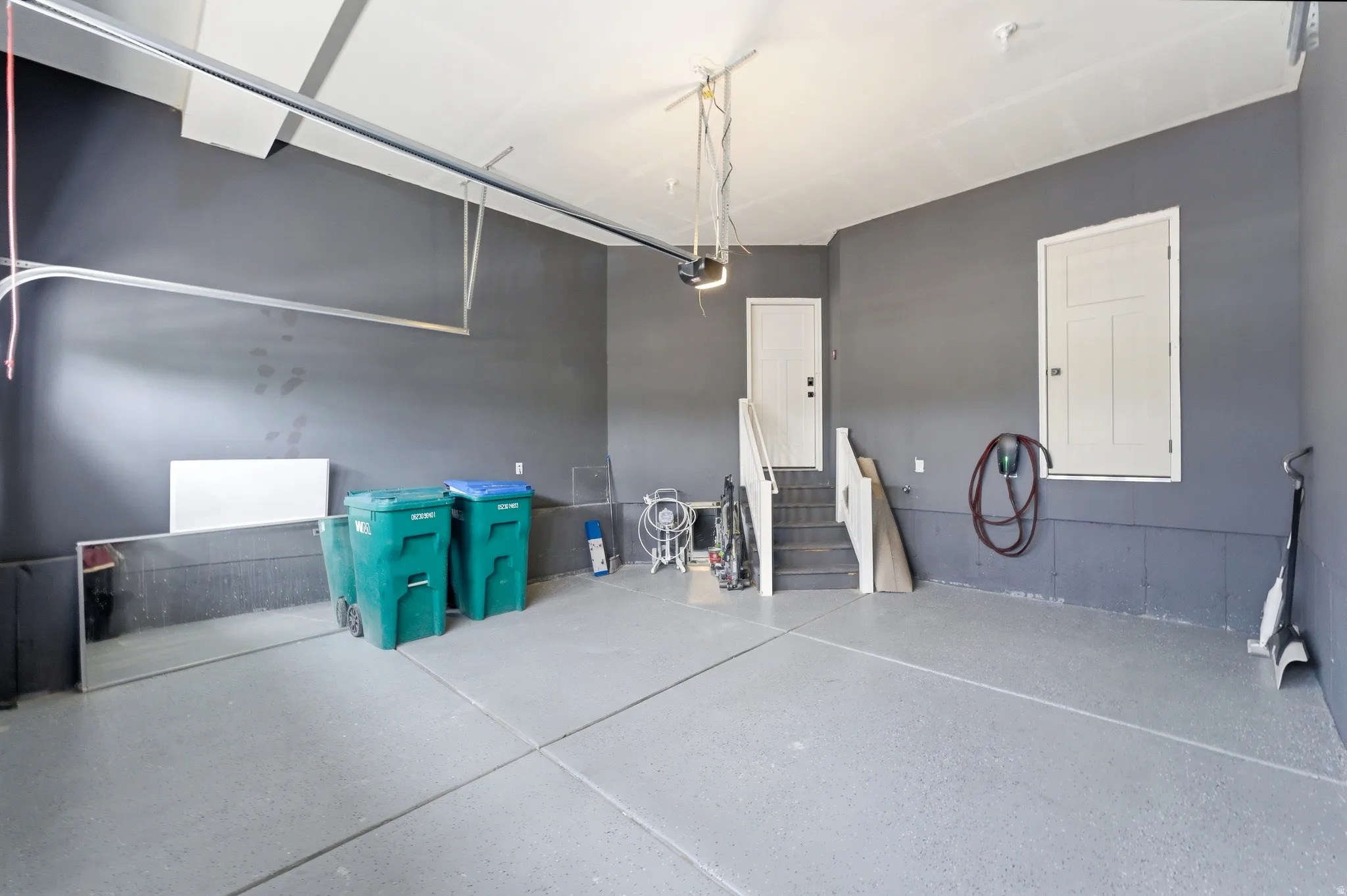 Spacious garage featuring a durable epoxy floor, direct entry access, and a dedicated EV charging station