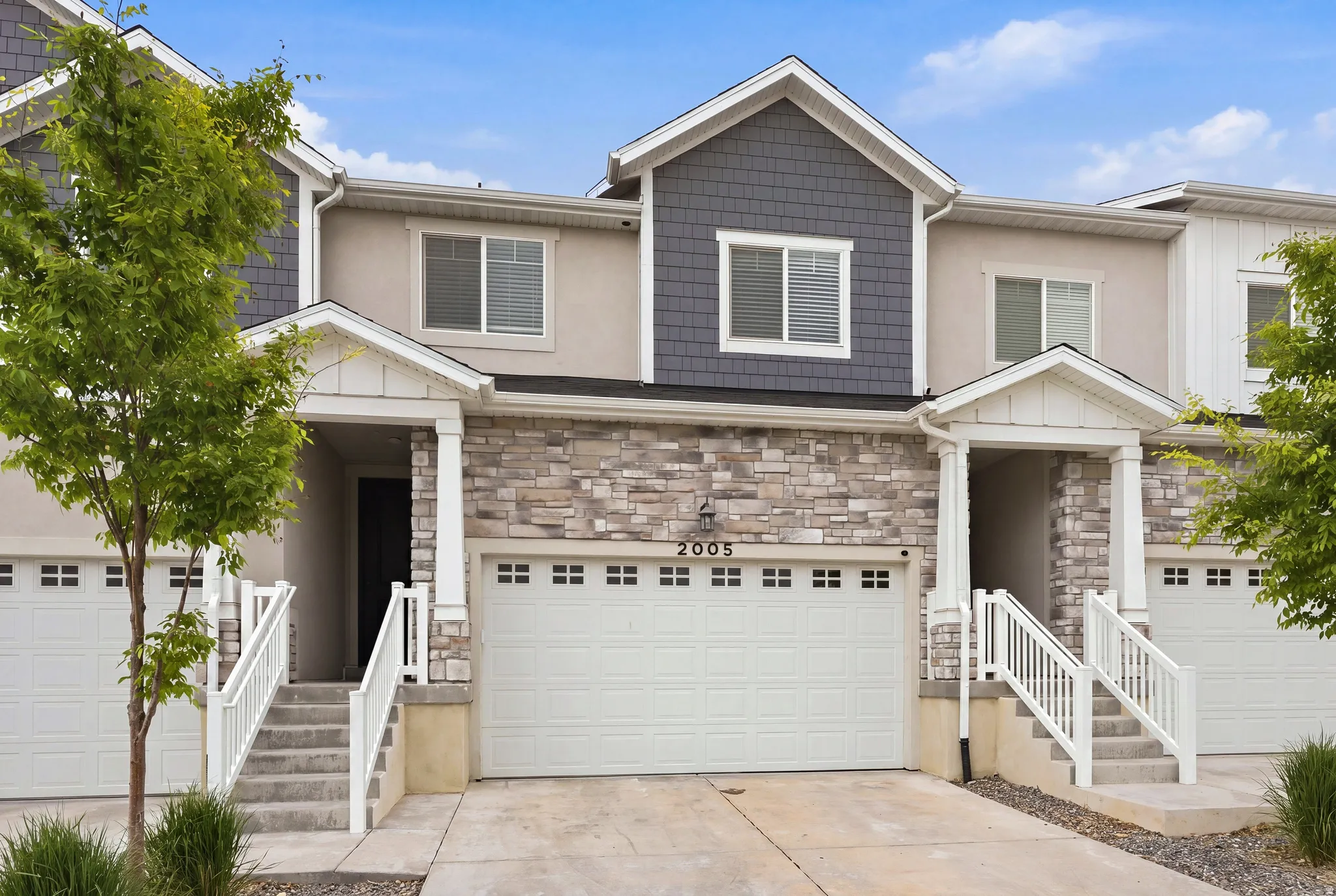 Contemporary townhome exterior featuring stone veneer, shake siding, and stucco accents