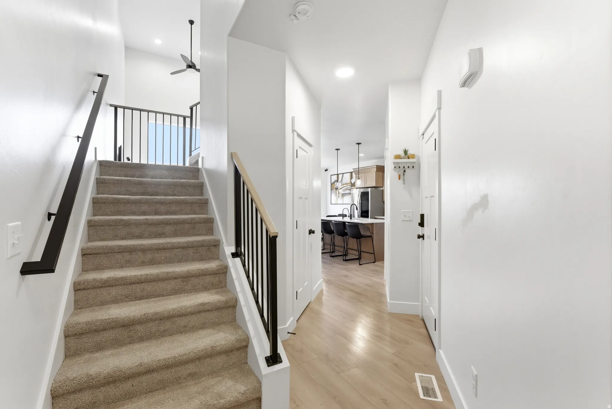 Carpeted staircase with black metal railings and a light wood-finish handrail