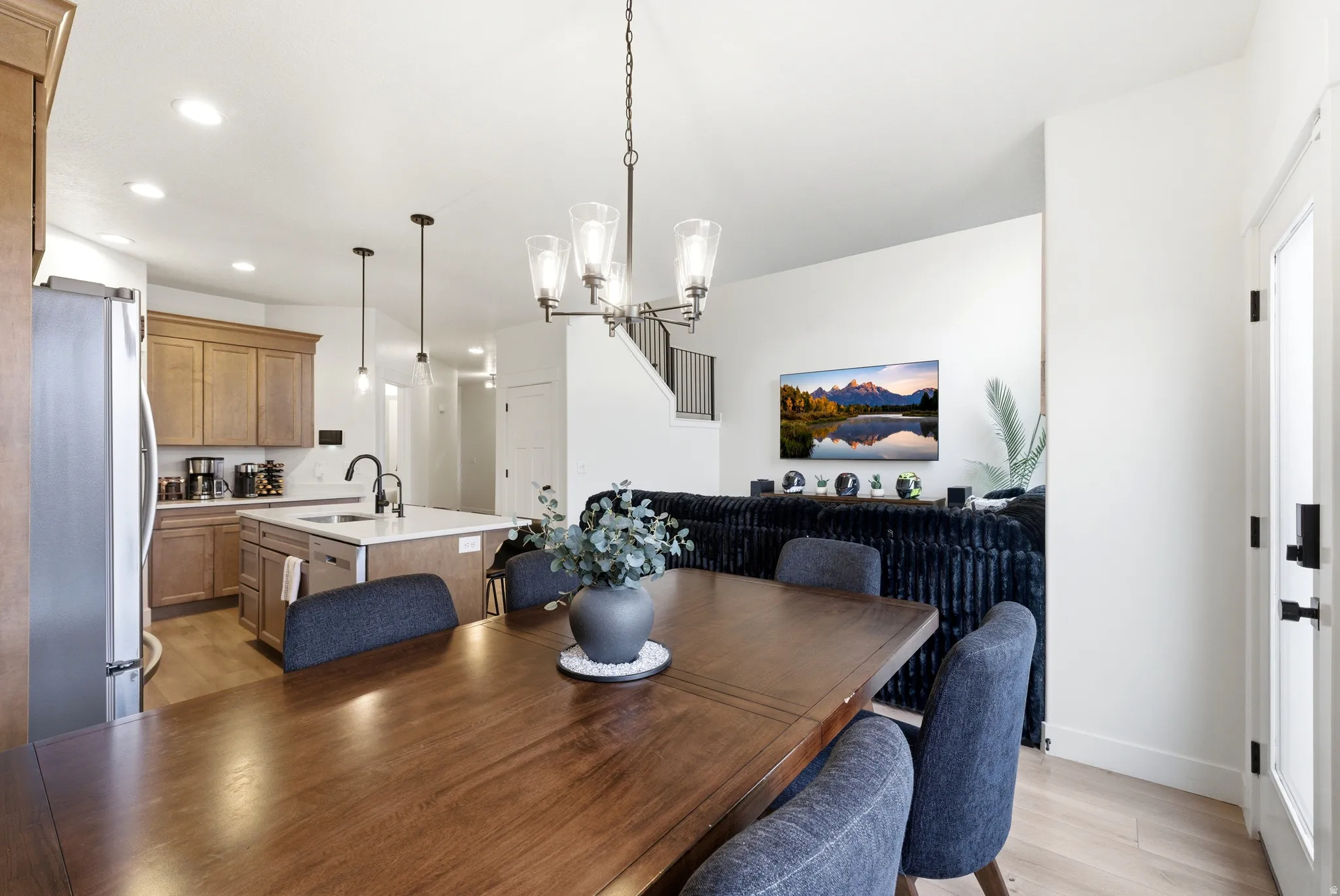 Open-concept dining area featuring a wood-finish floor and a multi-light chandelier
