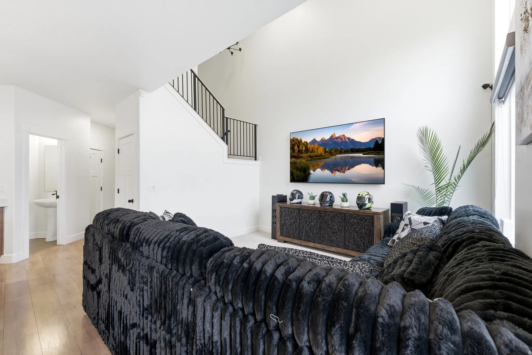 Living area featuring high ceilings, wood-finish flooring, and a contemporary black metal staircase railing