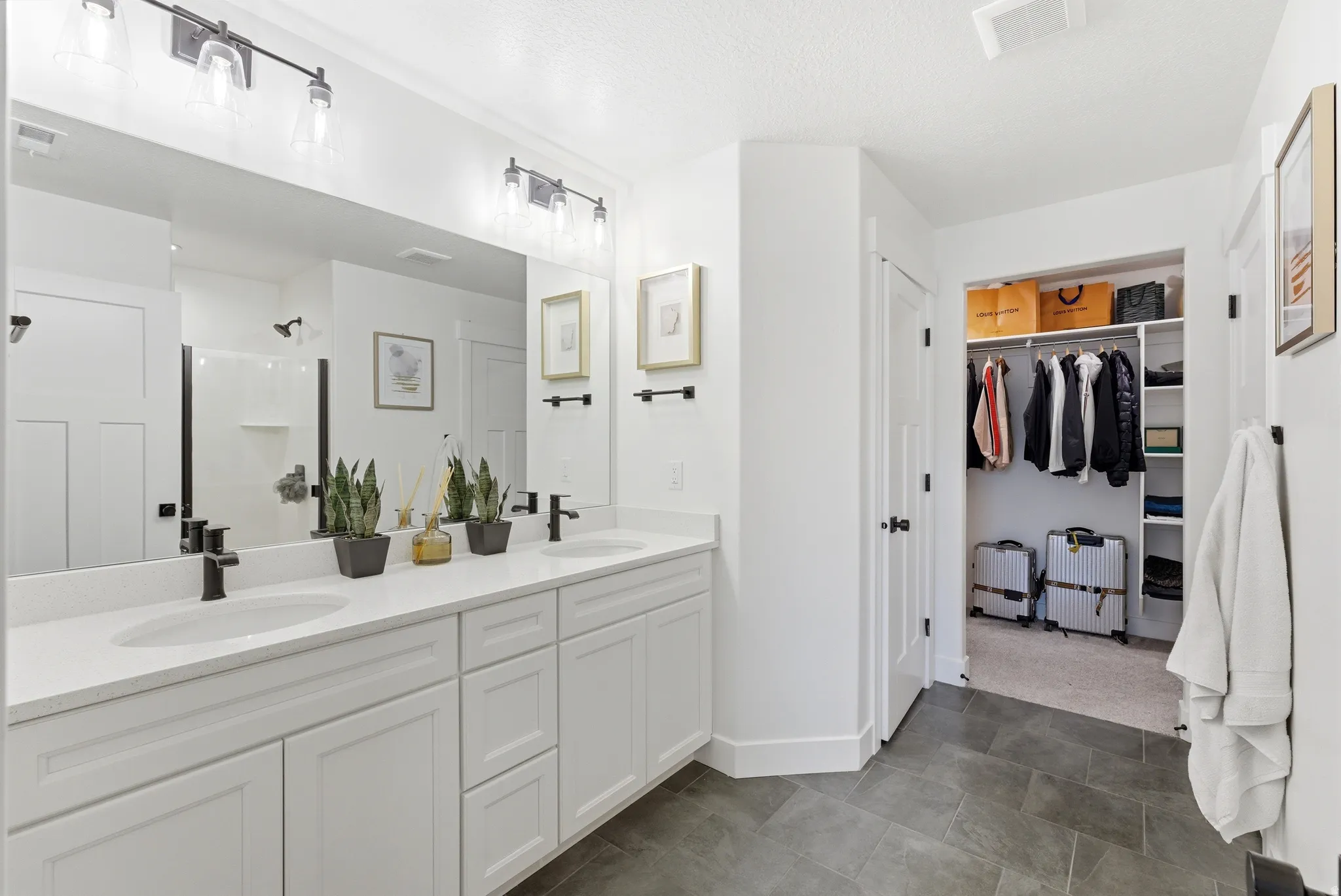 Double vanity featuring white cabinetry and countertops, undermount sinks, and matte black fixtures