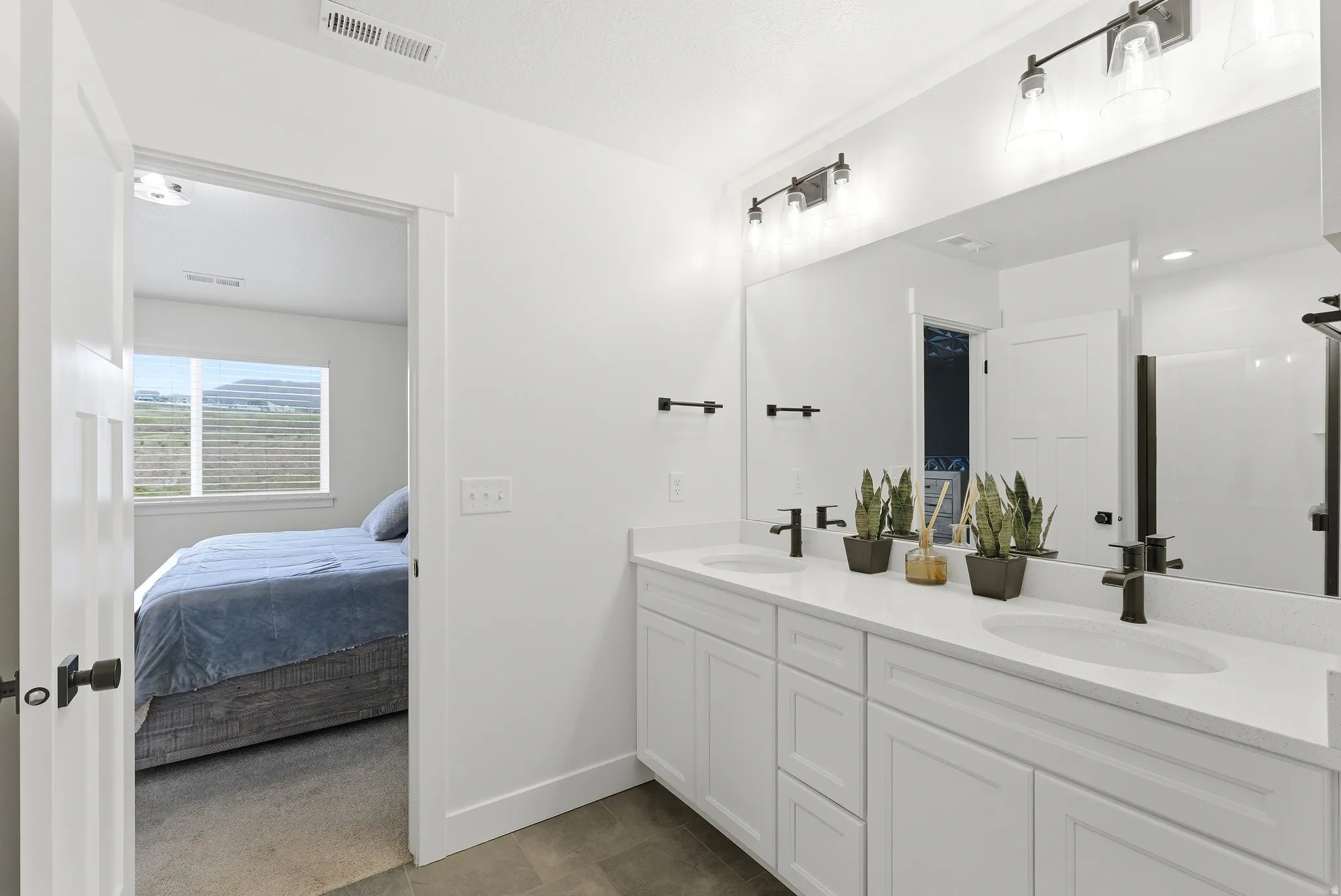 Double vanity with white cabinetry, light countertops, and matte black fixtures