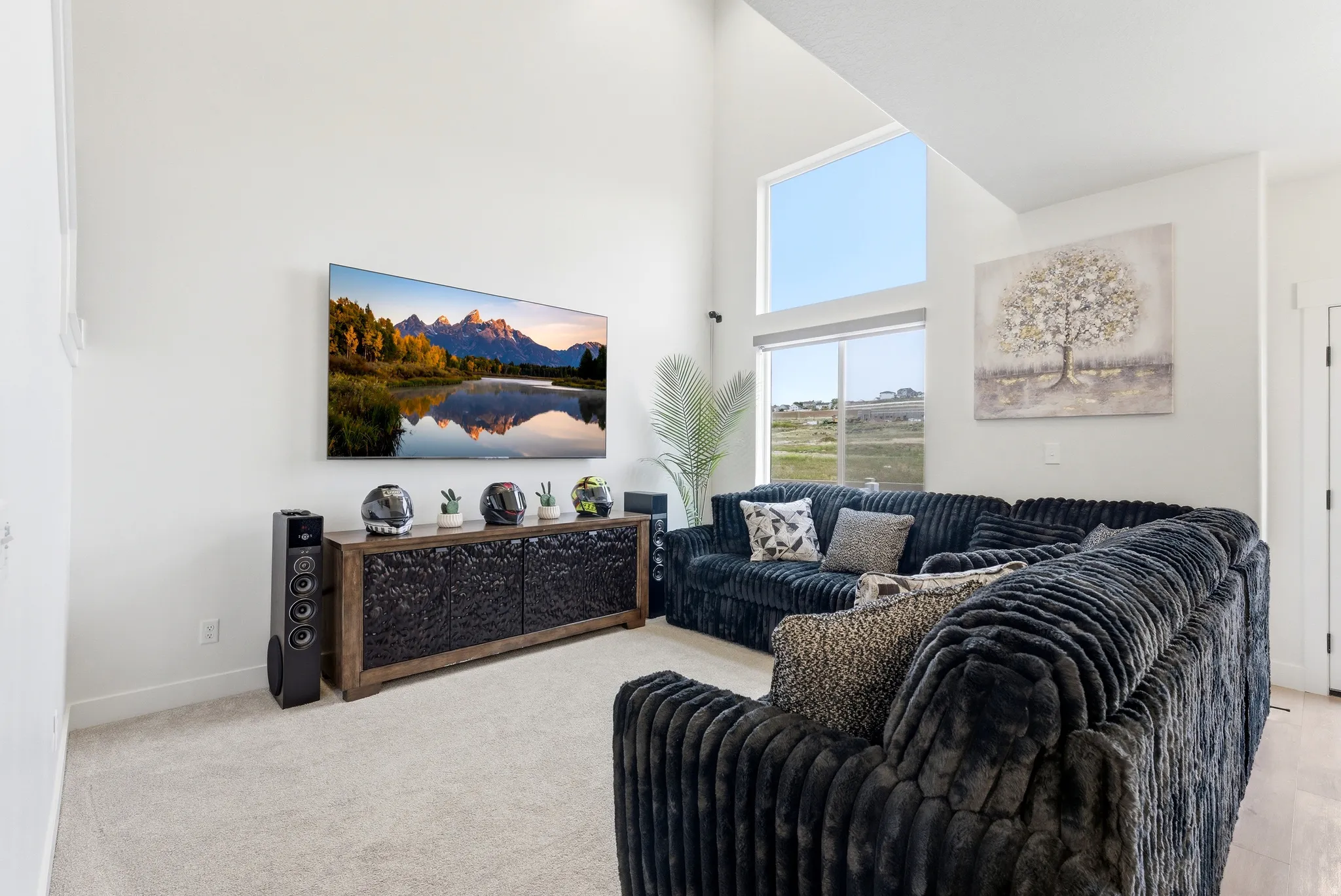 Living room featuring vaulted ceilings, large picture windows, light-colored carpeting, a wall-mounted television, and a built-in media console