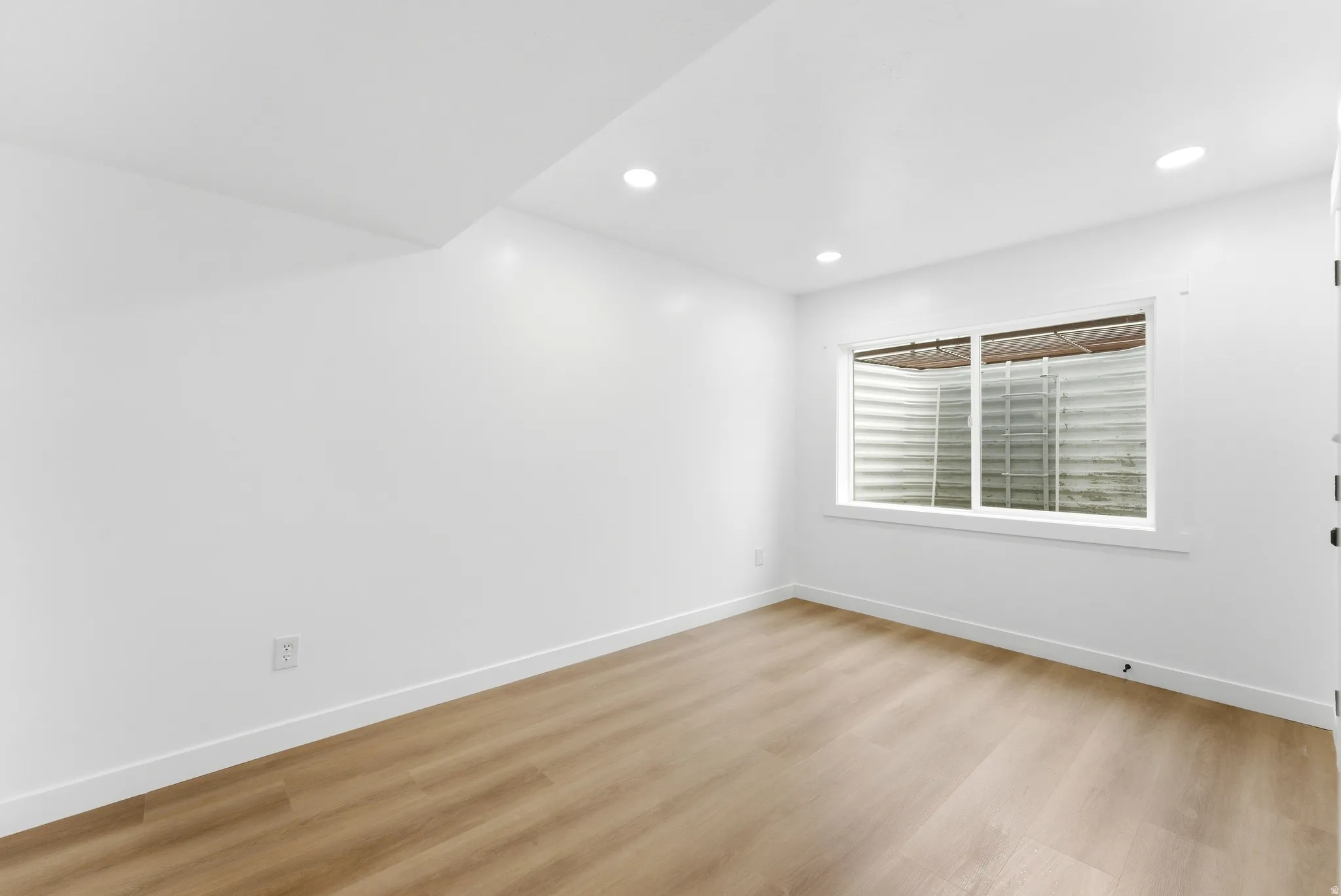 Open room with light wood-finish flooring and recessed ceiling lighting