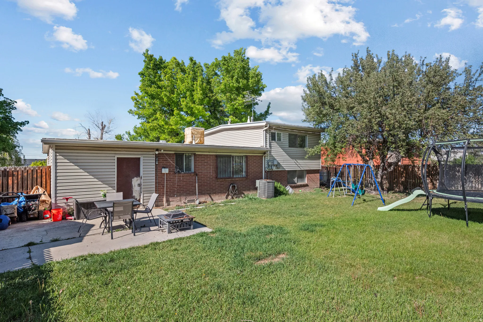 Expansive backyard featuring a lush lawn, mature trees, and a concrete patio