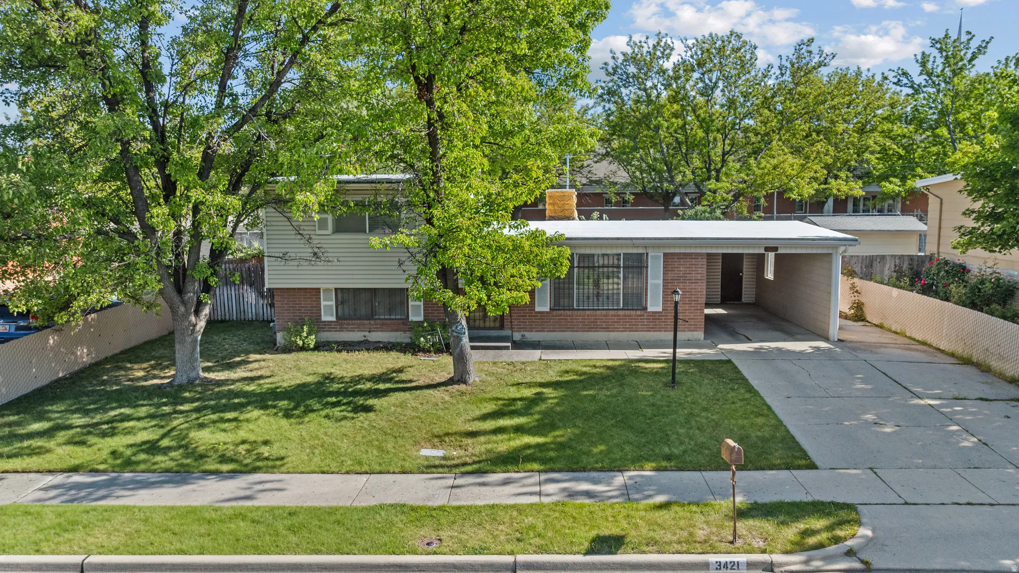 Split-level residence featuring a brick facade, green siding, and a covered carport