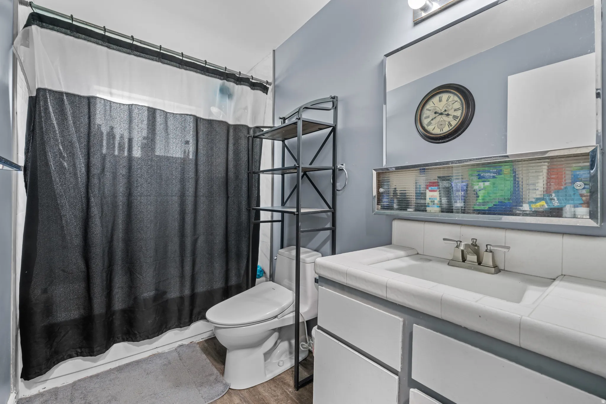 Bathroom featuring a built-in shower, white tiled vanity with integrated sink, and wood-finish flooring