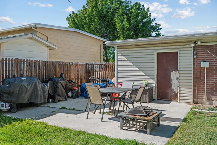 Rear concrete patio featuring a detached storage shed with siding