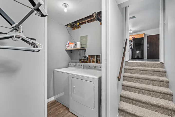 Dedicated laundry area featuring a washer and dryer with wood-finish flooring