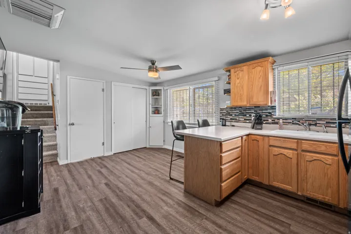 Kitchen featuring wood-finish flooring, oak cabinetry, white countertops, and a mosaic tile backsplash
