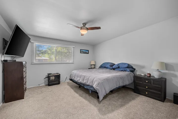 Carpeted room featuring a ceiling fan with integrated lighting, a window with horizontal blinds, and light gray wall paint