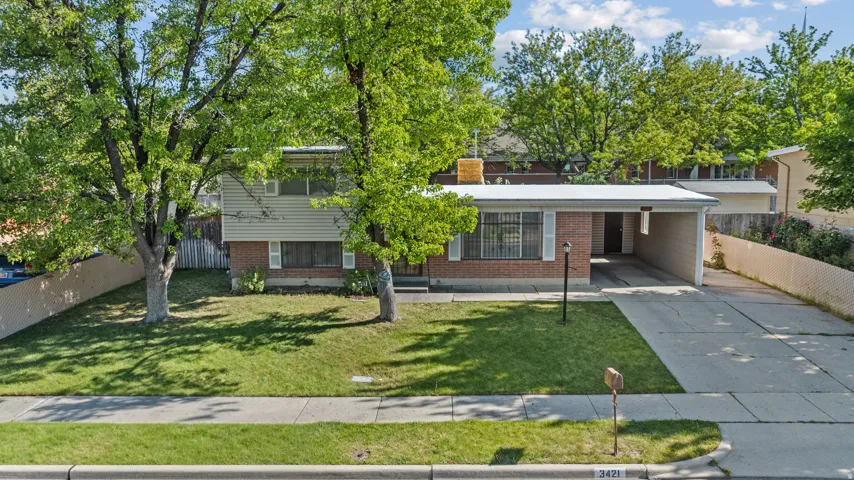 Split-level residence featuring a brick facade, green siding, and a covered carport