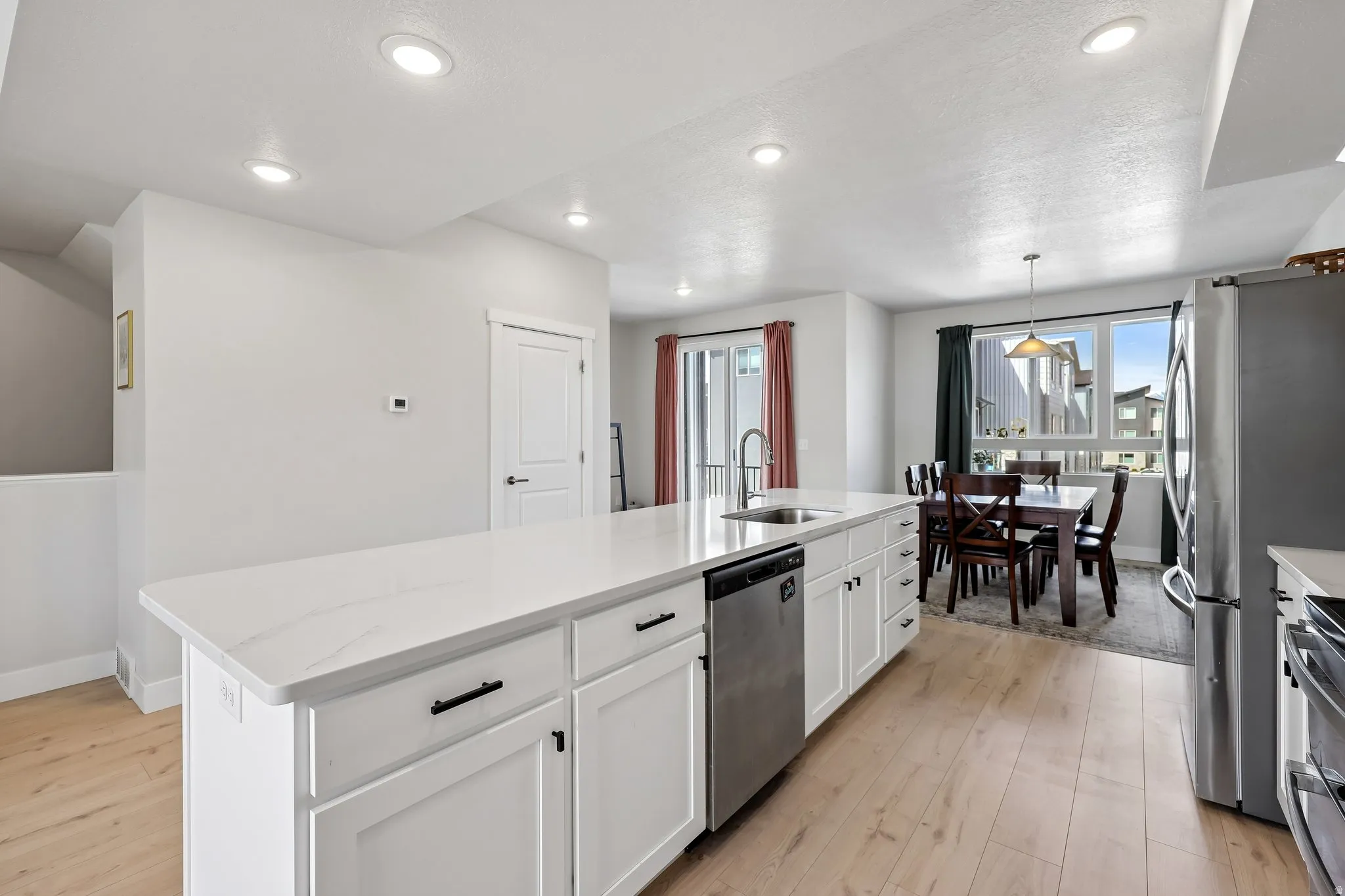 Kitchen featuring a center island with sink, light wood finished floors, healthy amount of natural light, and a textured ceiling
