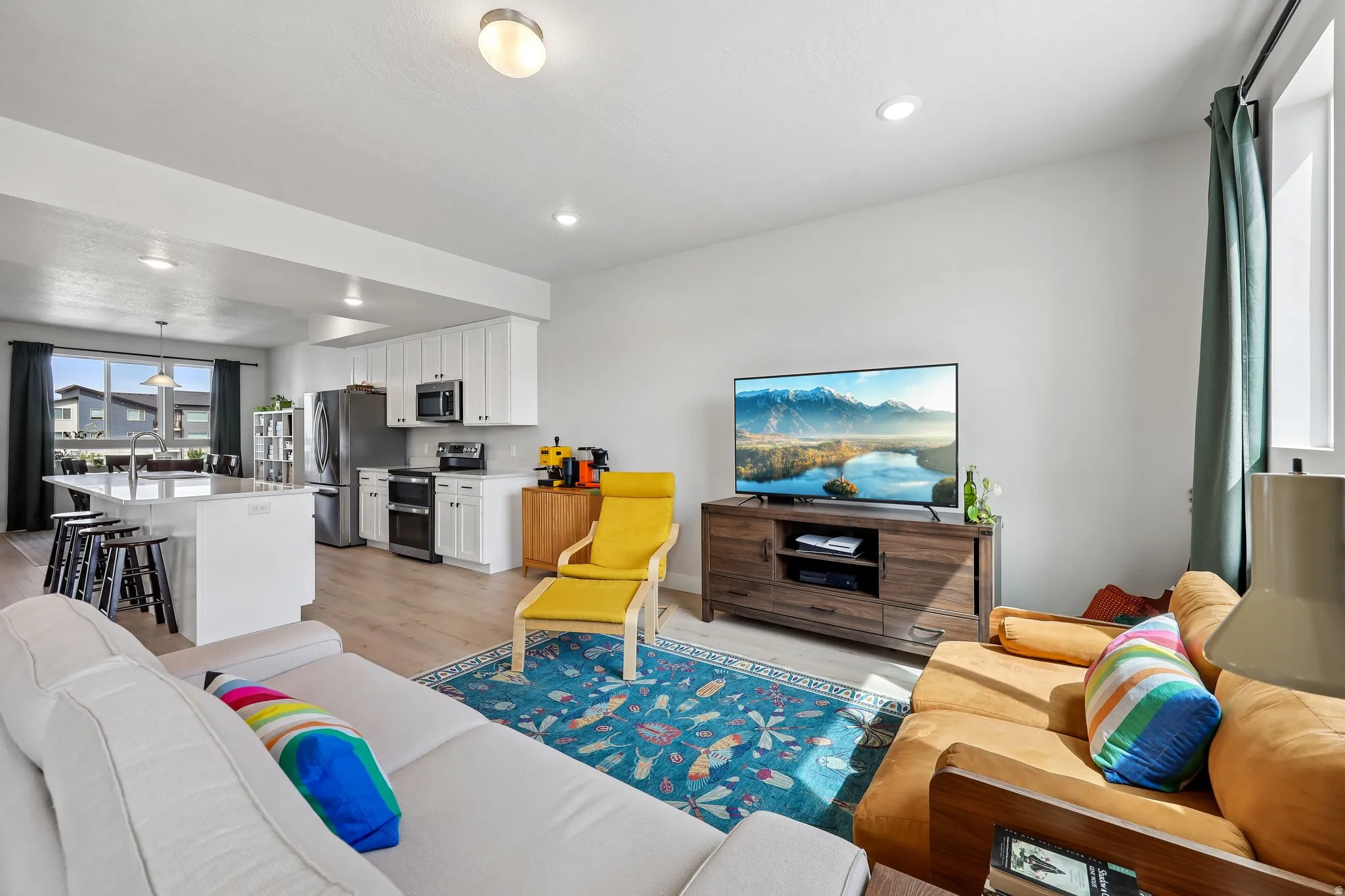 Living area with light wood finished floors and recessed lighting