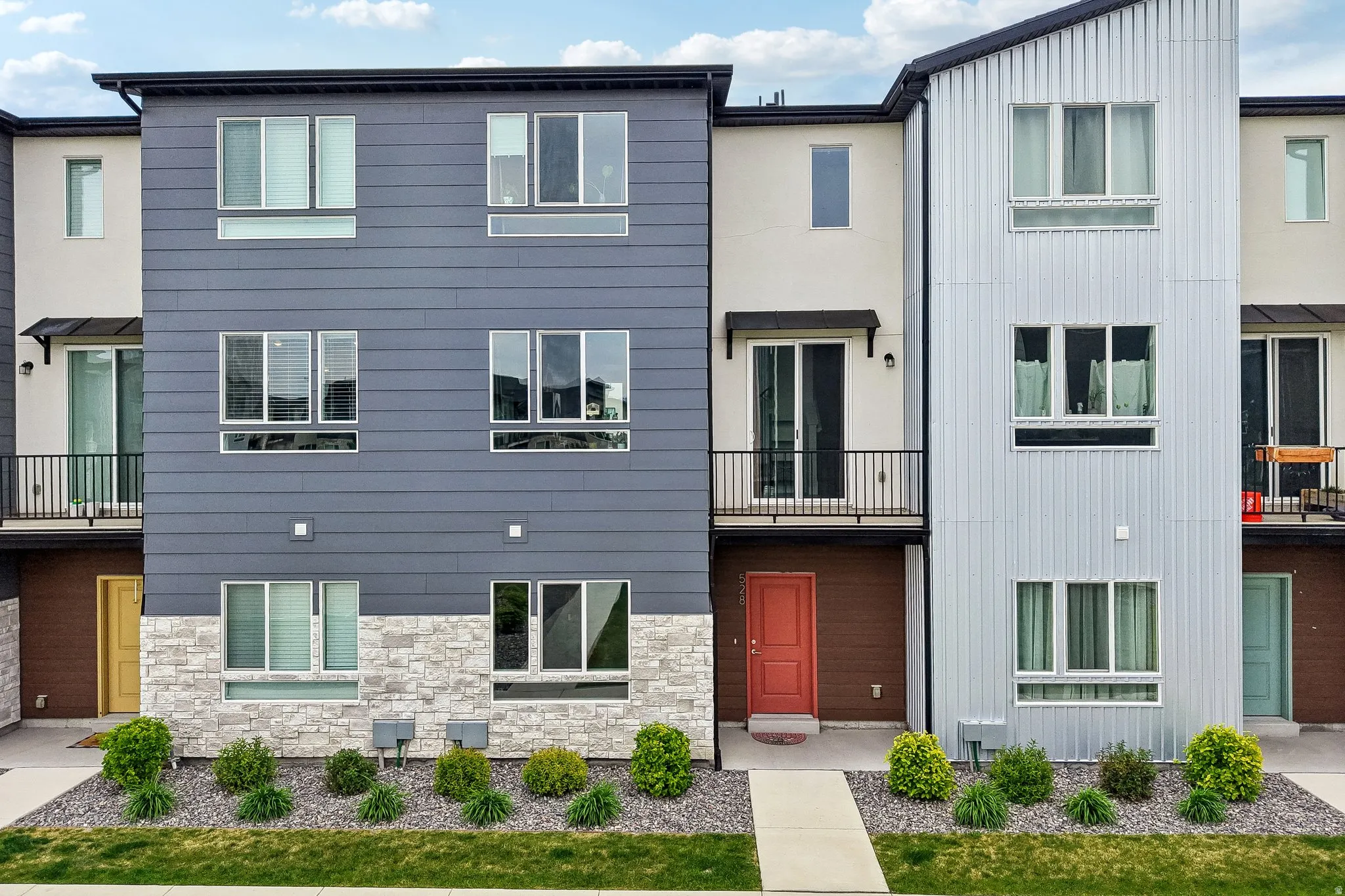 View of front of house featuring a balcony, board and batten siding, and stone siding