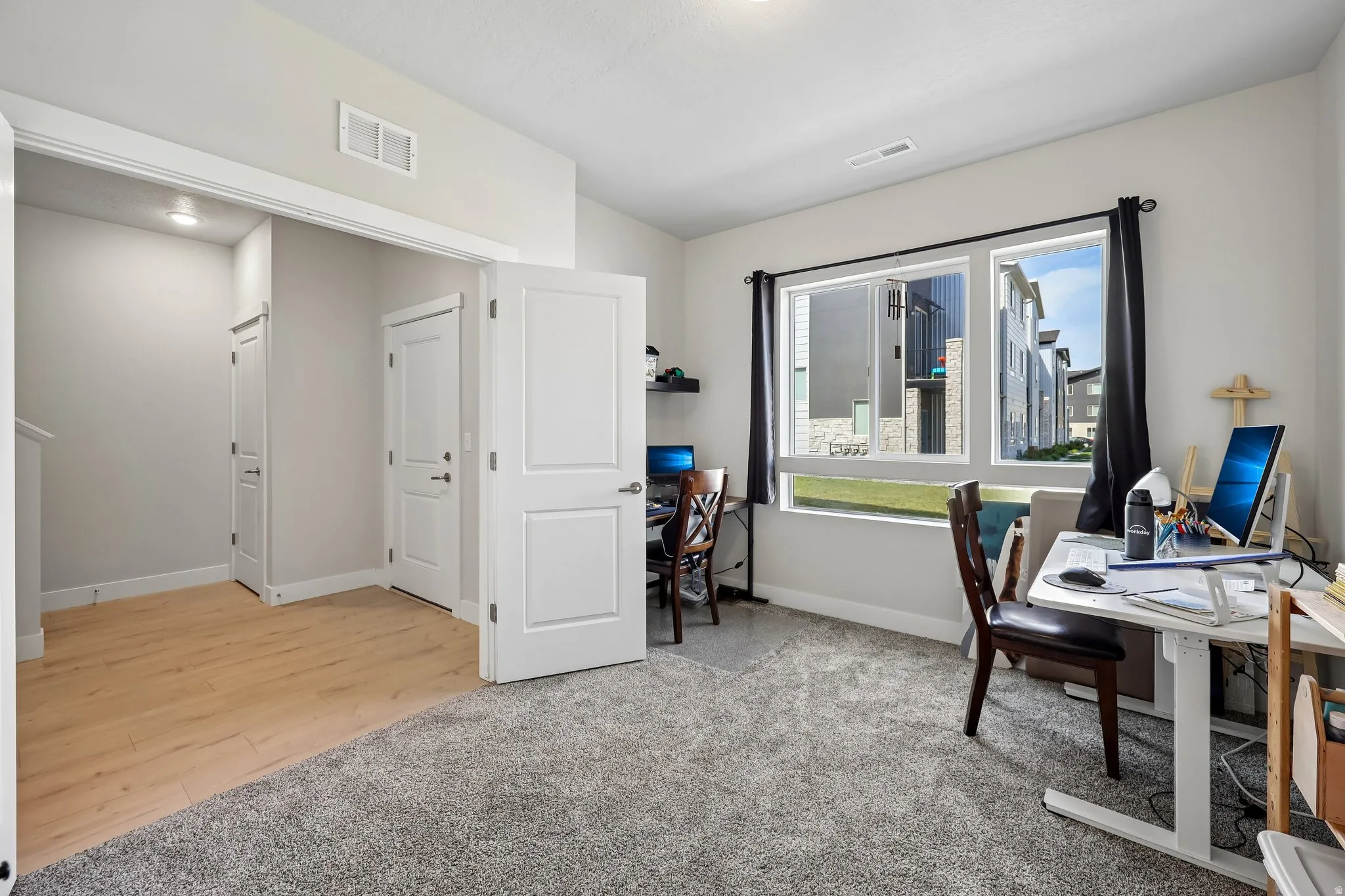 Office area with light colored carpet and light wood-type flooring