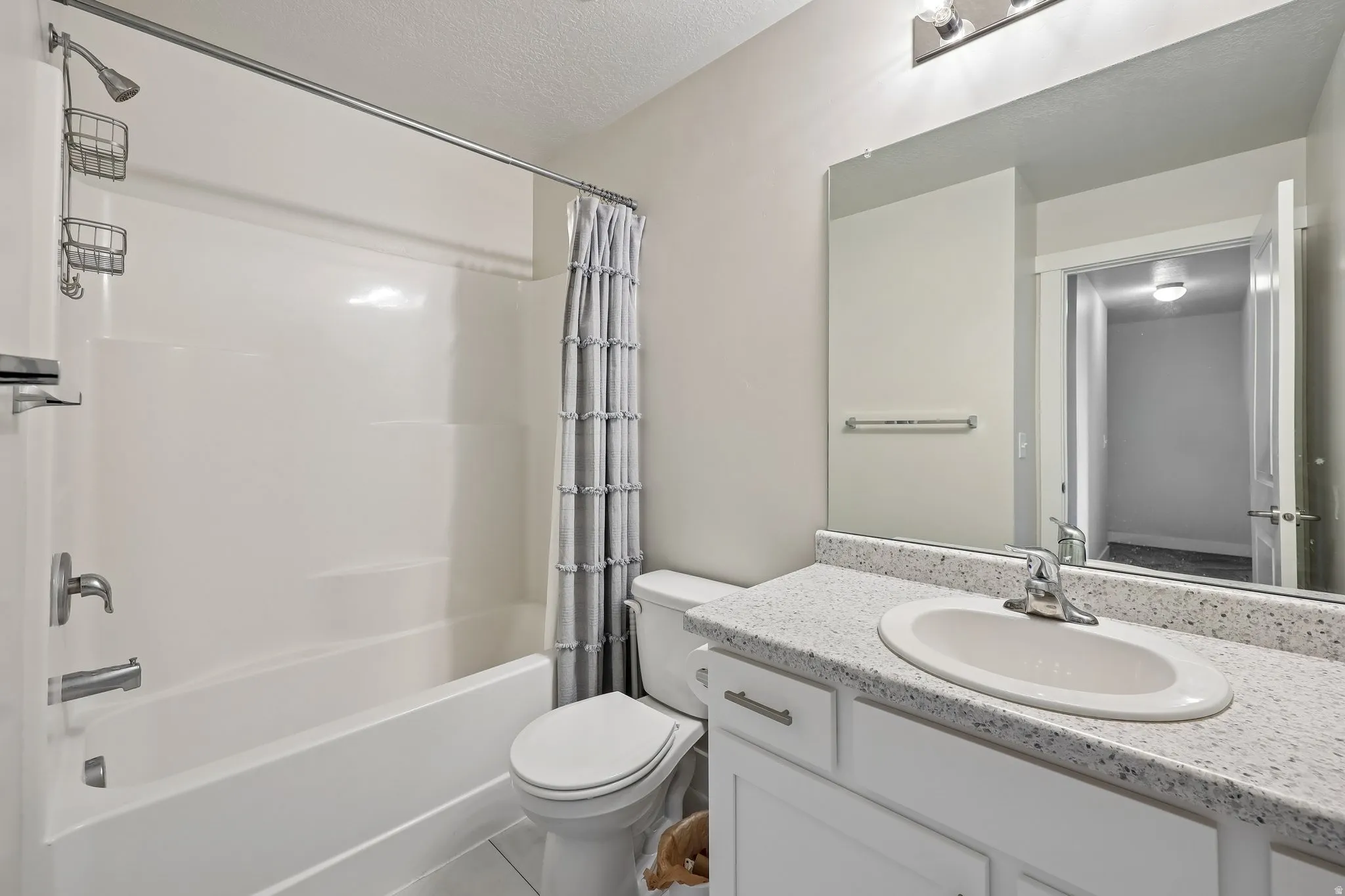 Bathroom with vanity, shower / tub combo, and a textured ceiling