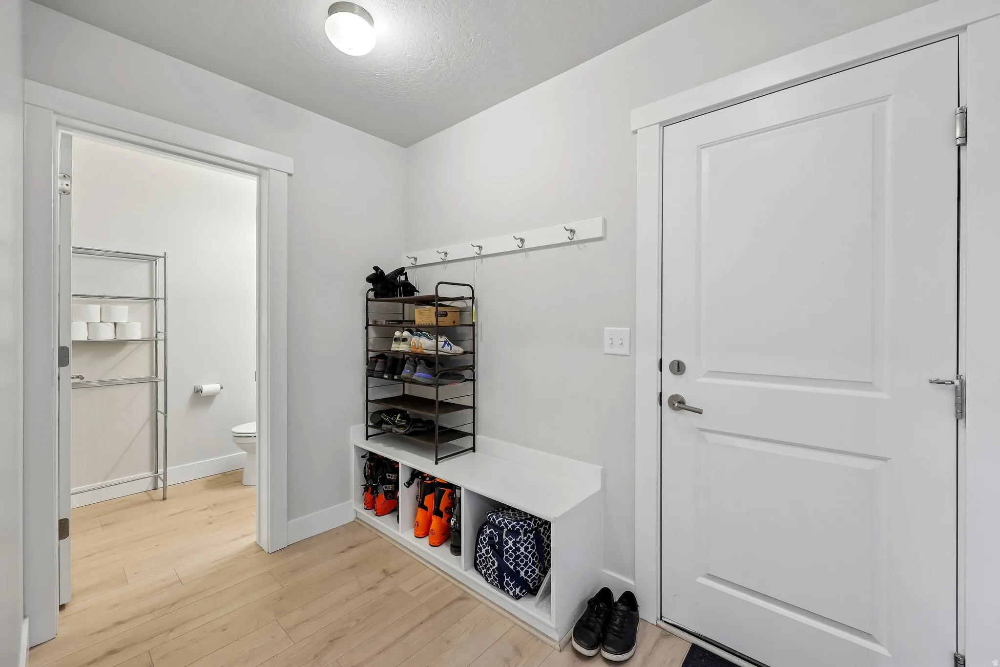 Mudroom featuring light wood finished floors and a textured ceiling