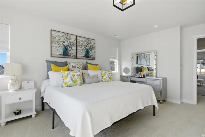 Plush carpeted bedroom featuring a window with a roller shade, a white nightstand, and a contemporary ceiling light fixture