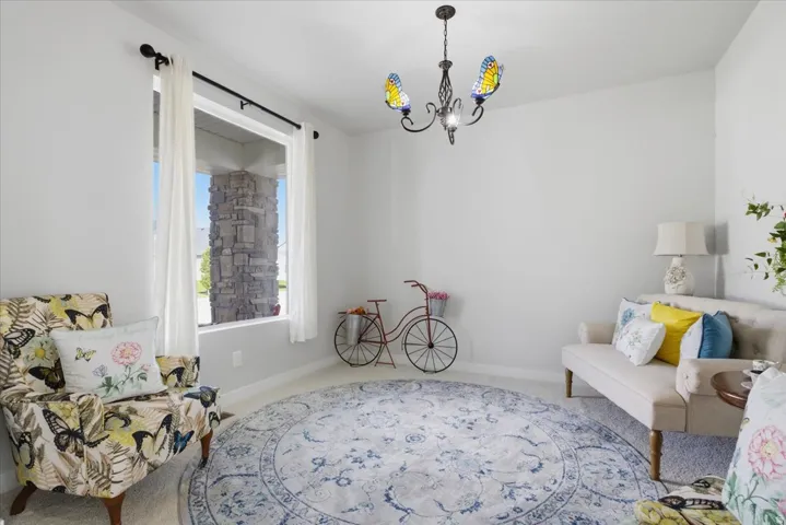 Well-lit room featuring a large window, a decorative chandelier with colorful glass shades, and light-colored walls