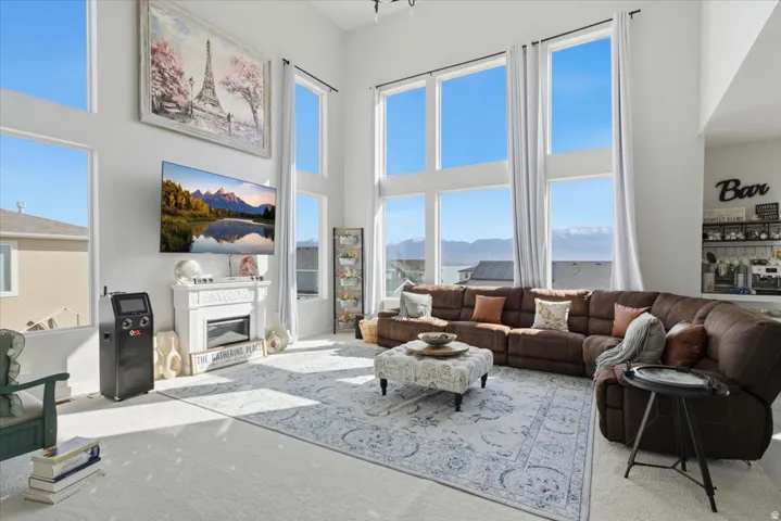 Two-story living area featuring a white electric fireplace with mantel, built-in shelving, high ceilings, and large picture windows