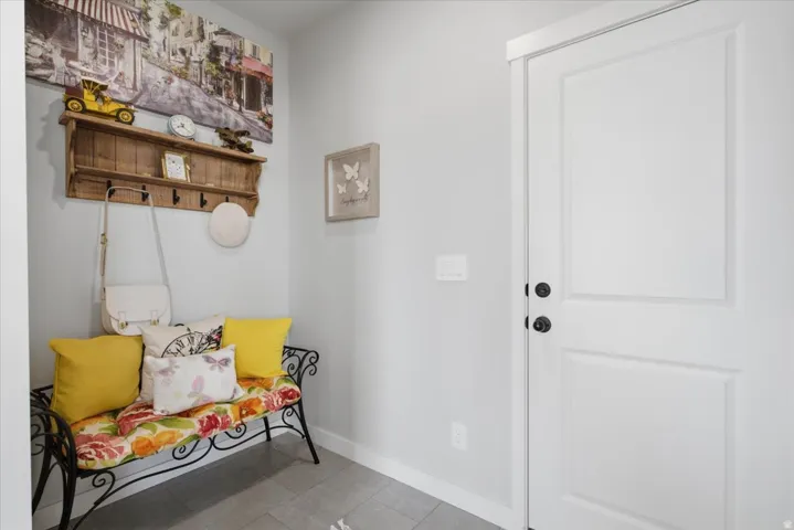 Entryway featuring a paneled door with matte black hardware, light gray walls, white baseboards, and gray tiled flooring