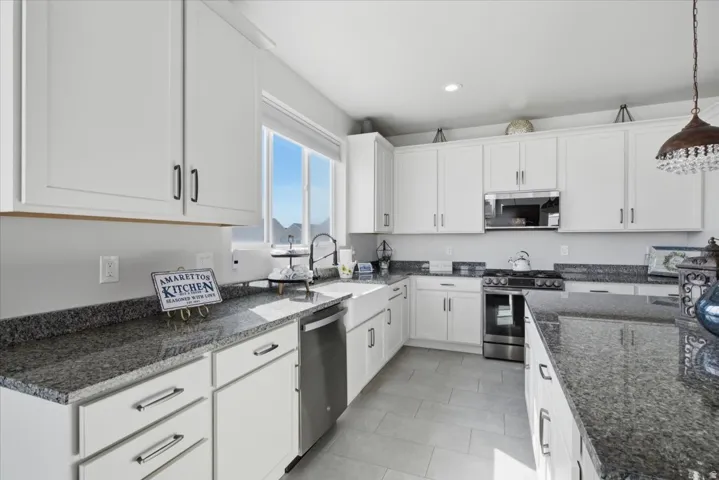Modern kitchen featuring white shaker-style cabinetry, granite countertops, and stainless steel appliances