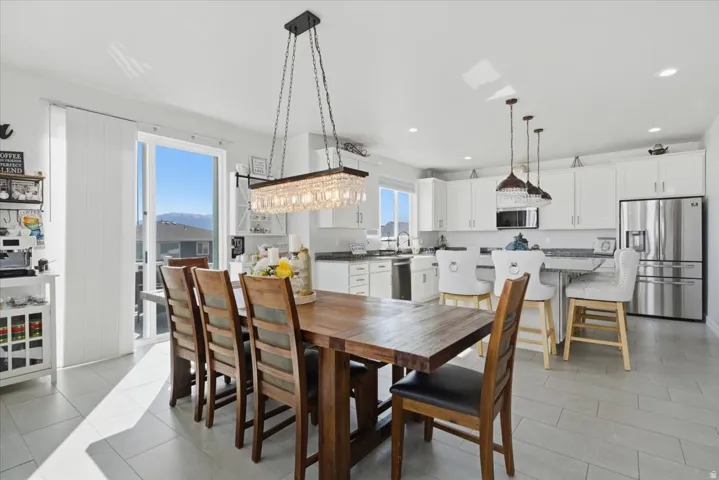 Open-concept dining area featuring a rectangular wood dining table, a crystal chandelier, and large sliding glass doors