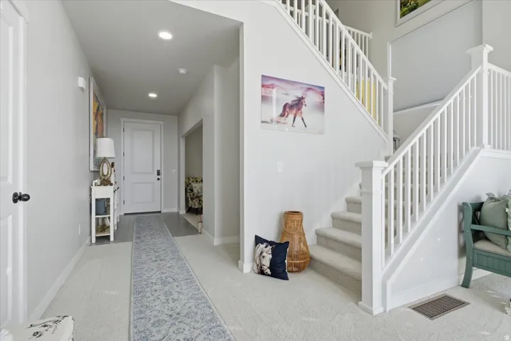 Two-story entryway featuring a carpeted staircase with white balusters