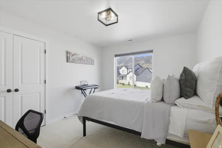 Bright room featuring a large window, plush carpeting, a modern ceiling light fixture, and white double doors
