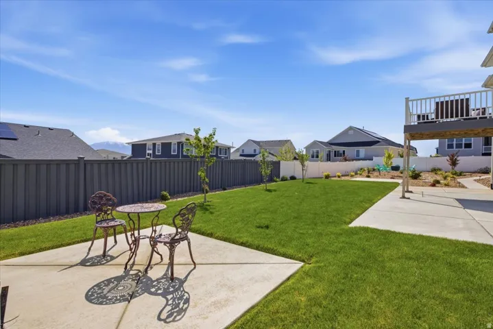 Expansive backyard featuring a manicured lawn, concrete patio, and a privacy fence