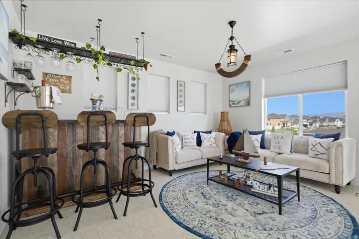 Bright living space featuring a built-in bar with wood-finish paneling, a large window, recessed lighting, and an overhead lighting fixture