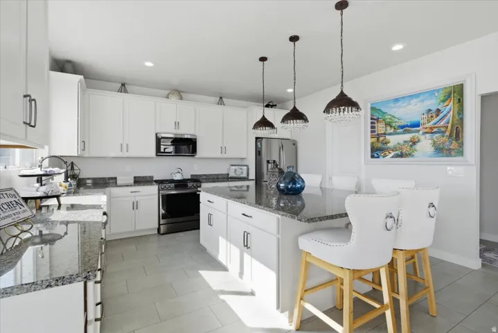 Bright kitchen featuring an island with three pendant lights and built-in white cabinetry
