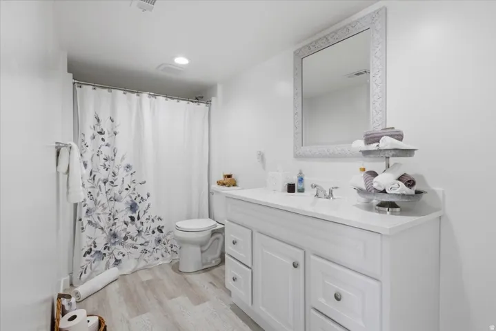 Bathroom featuring a single vanity with storage, light-toned wood-finish flooring, and a shower-tub combination