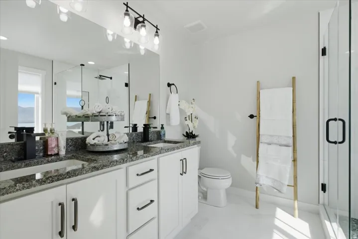 Bathroom featuring a dual vanity with undermount sinks, stone countertops, and matte black fixtures