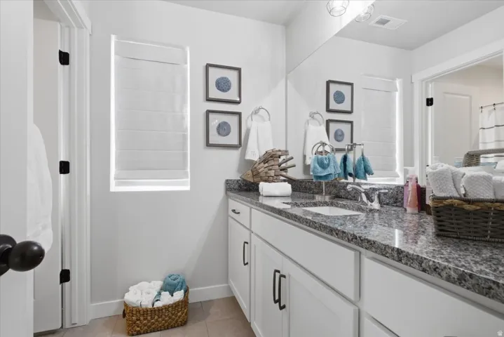 Bathroom featuring a double vanity with stone countertops, integrated rectangular sinks, and white shaker-style cabinetry