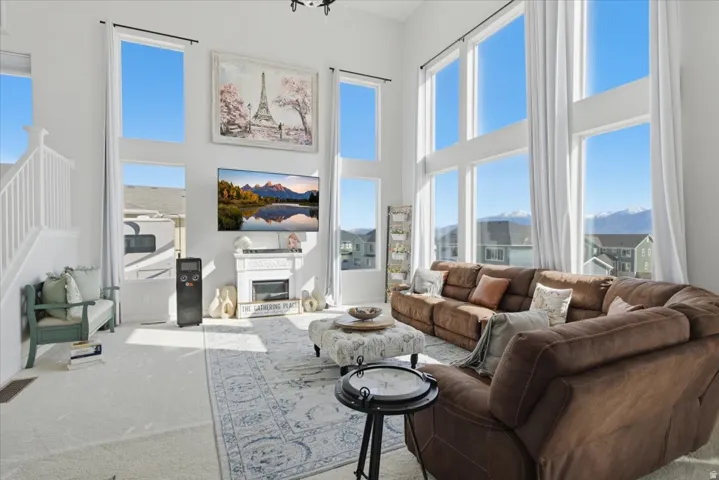 Two-story living area featuring a white fireplace mantel, large windows with mountain scenery, and white wall-mounted shelving