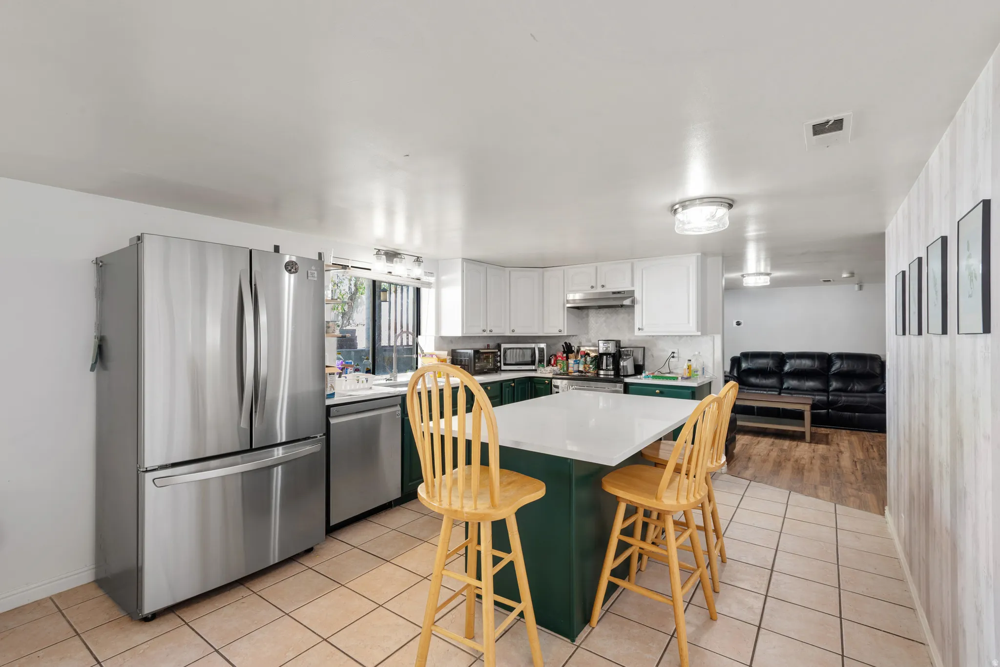 Well-appointed kitchen featuring stainless steel appliances, a center island with countertop seating, white upper cabinetry, and dark lower cabinetry