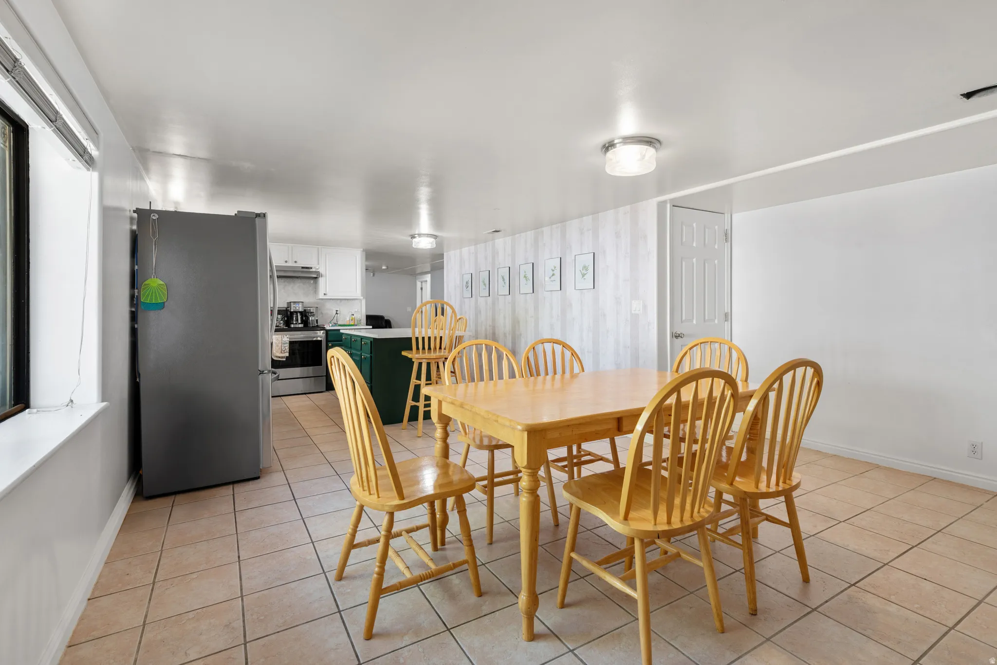 Open-concept kitchen and dining area featuring tile flooring, white walls, and a window providing natural light