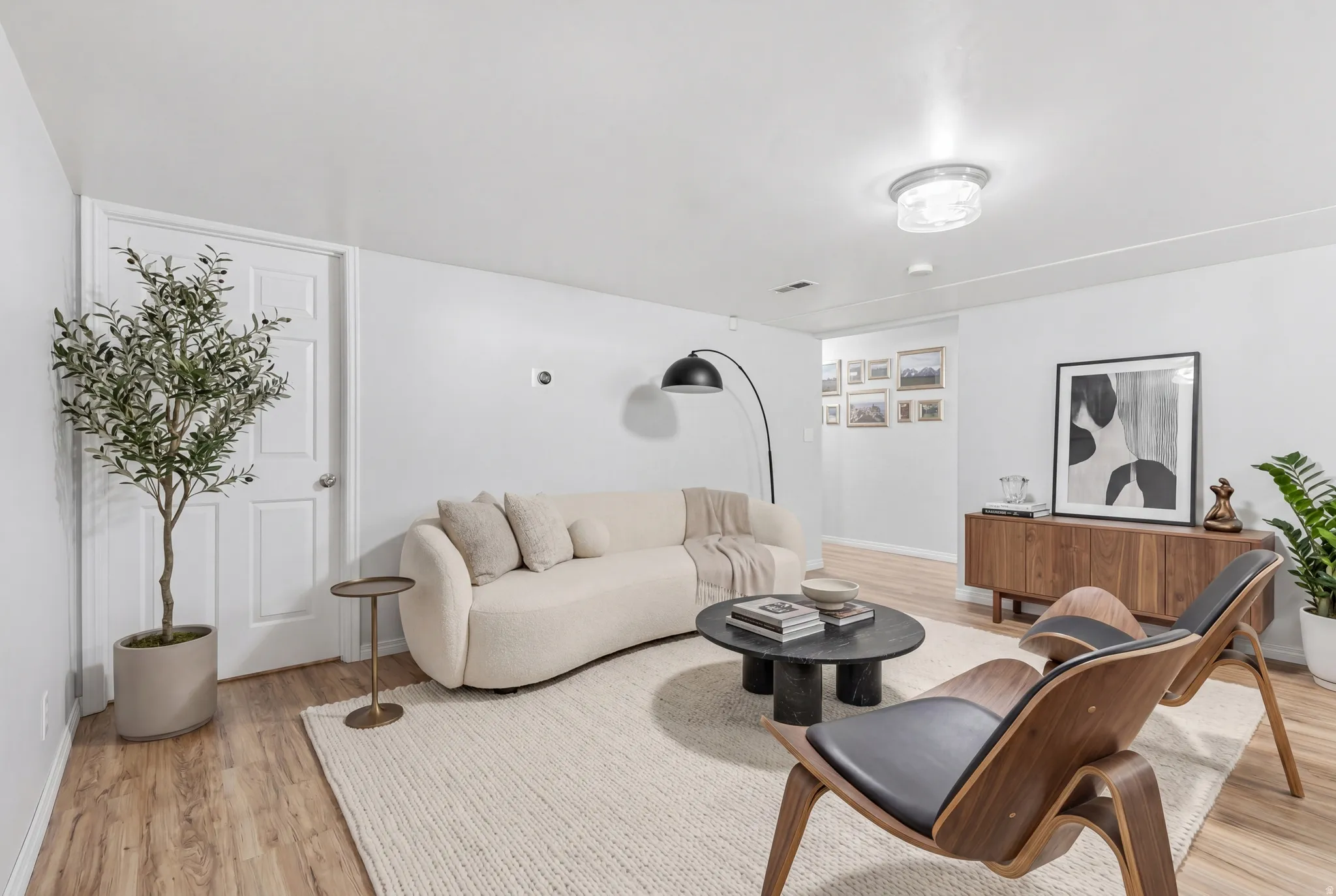 Spacious living area featuring light wood-finish flooring, white walls, and a recessed ceiling light
