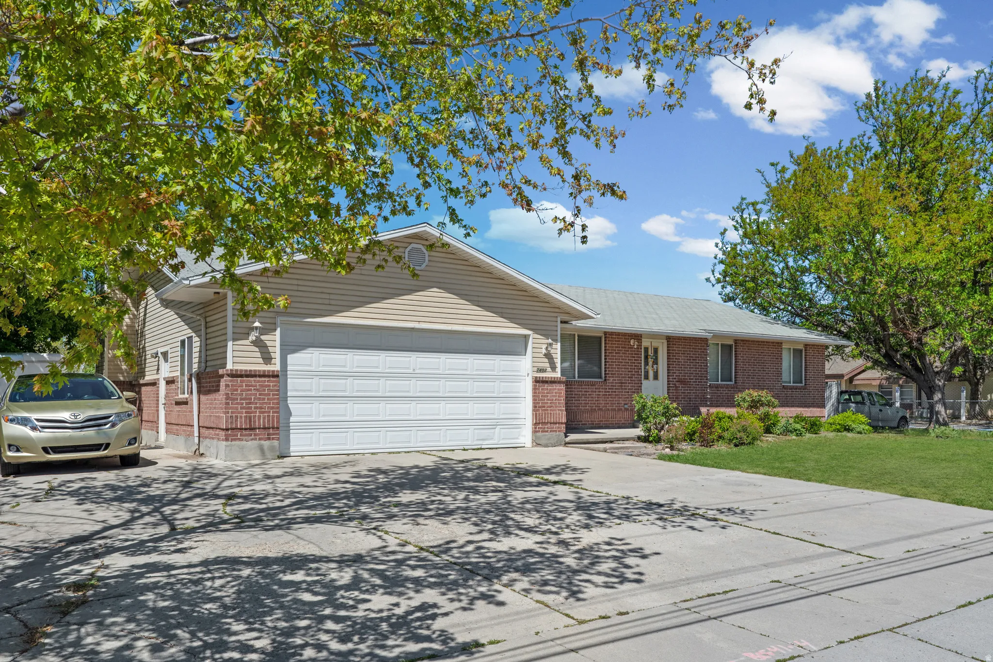 Ranch-style exterior featuring brick and siding, an attached two-car garage, and a concrete driveway