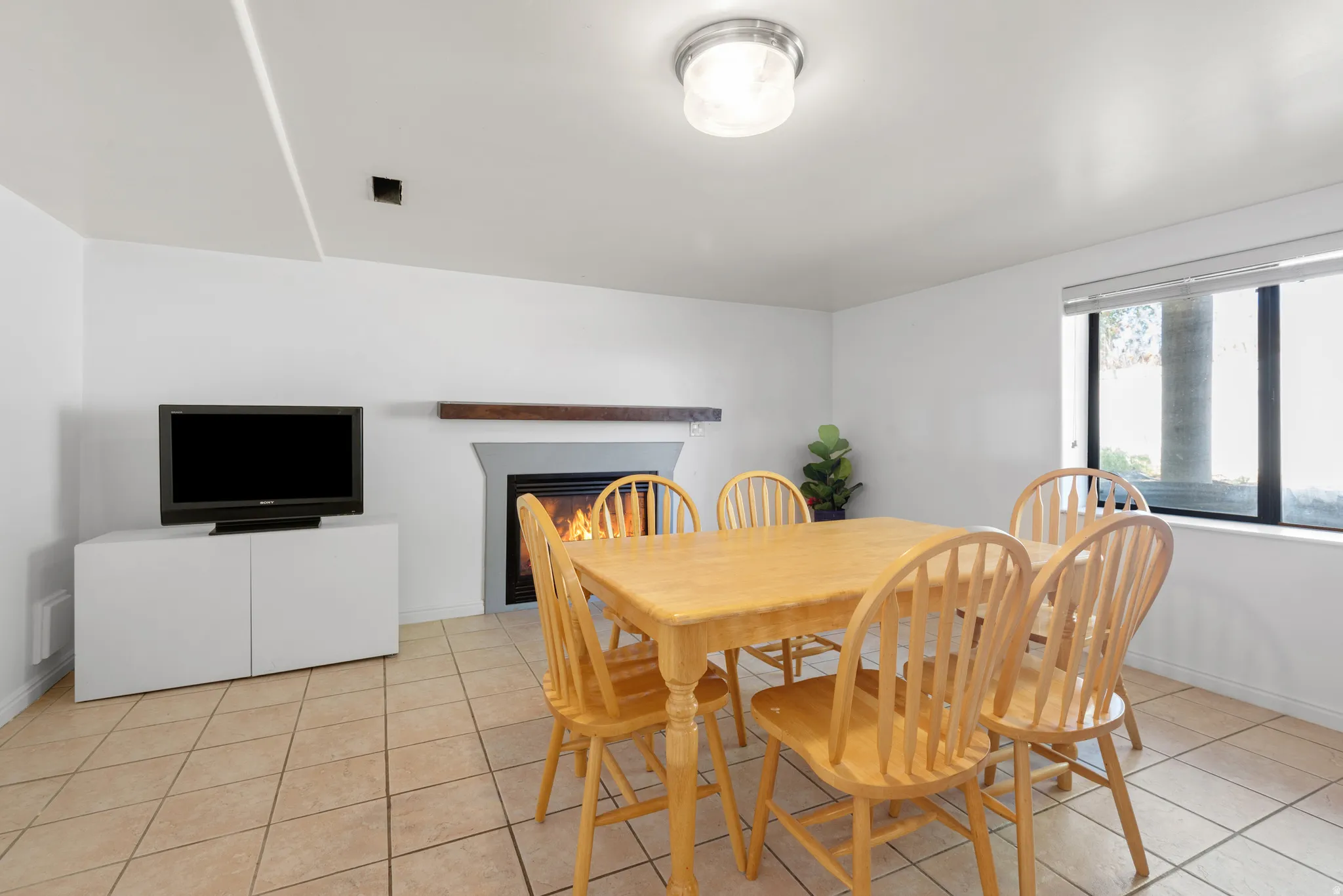Ceramic tile flooring throughout, featuring a fireplace with a wood mantle