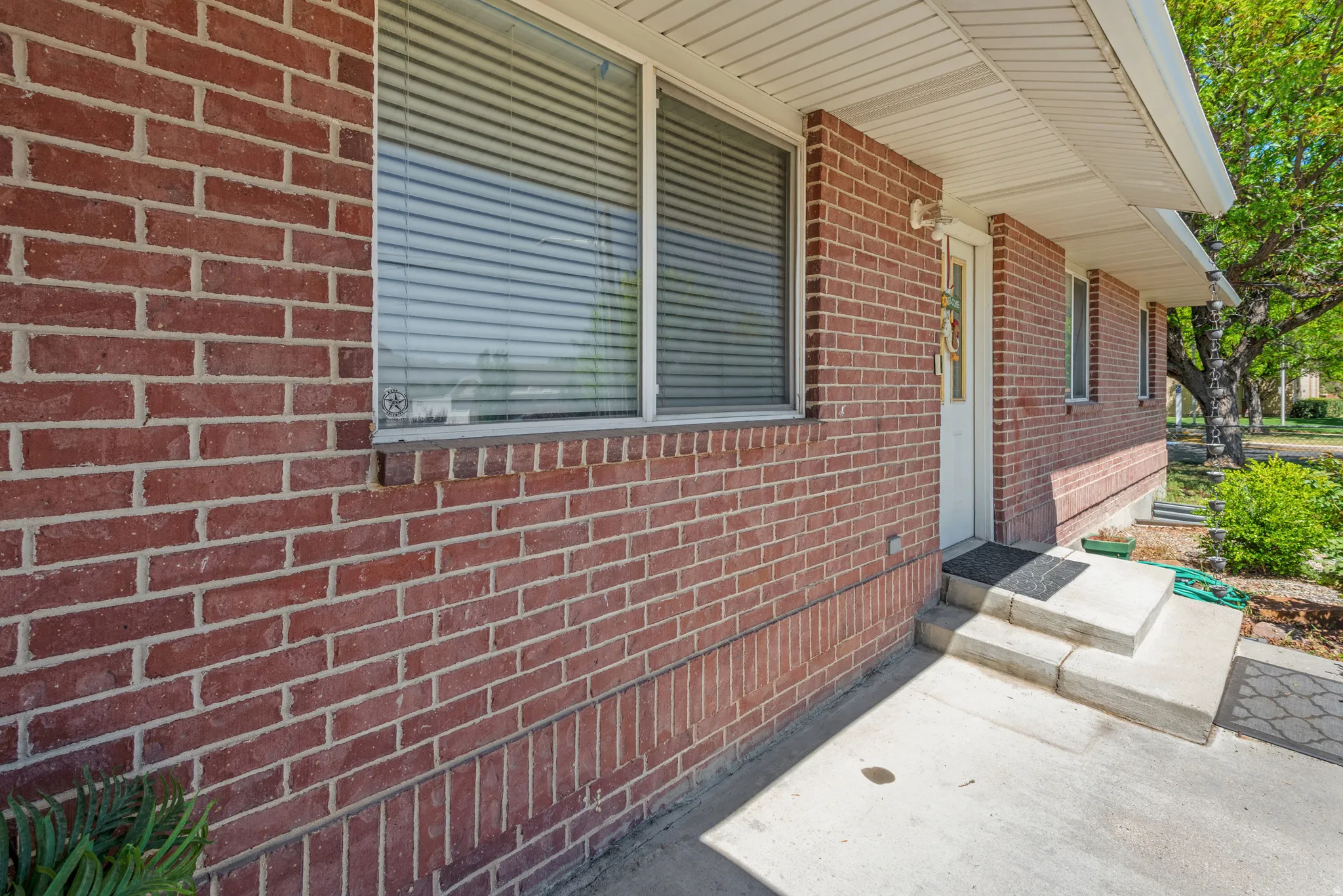 Red brick exterior with white trim windows and a white entry door