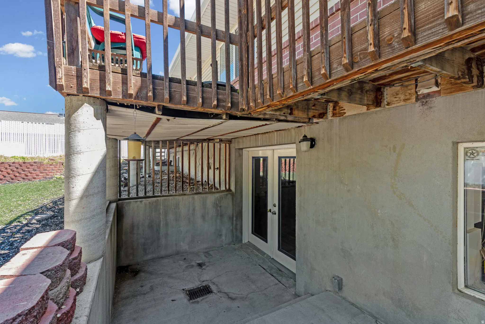 Walk-out basement patio with double French doors and an exterior wall light